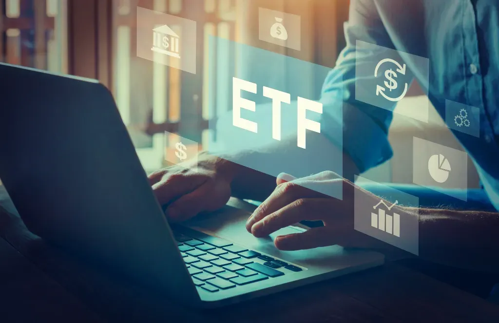 Mężczyzna siedzący przed laptopem, sprawdzający fundusze ETF